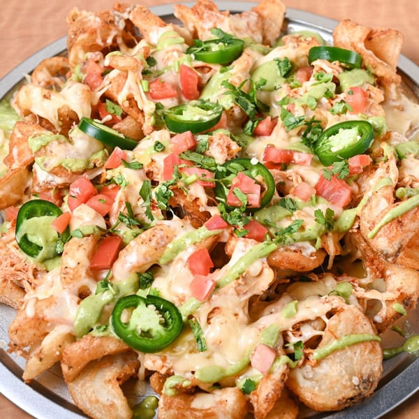 Crispy potato nachos with melted cheese, diced tomatoes, jalapeños, cilantro, and green sauce.