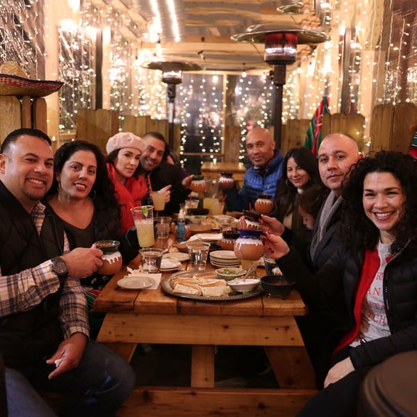 Group of friends enjoying Mexican food and drinks at Cesar's Killer Margaritas, surrounded by string lights.